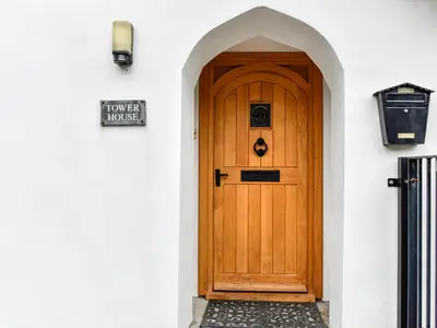 a wooden door in a white building with a sign on it at Tower House in Boscastle