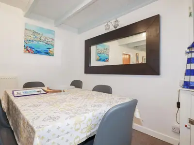 a dining room with a table and a mirror at Daisy Cottage in Perranporth