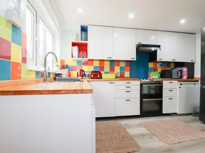 a kitchen with white cabinets and a sink at Daisy Cottage in Perranporth