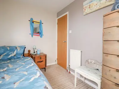 a bedroom with a bed and a desk and a chair at Daisy Cottage in Perranporth