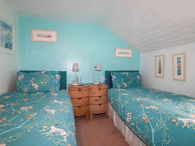 two beds in a bedroom with blue walls at Daisy Cottage in Perranporth