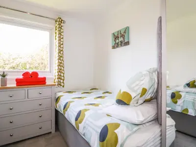 a bedroom with a bed and a dresser and a window at Hunrosa in Redruth
