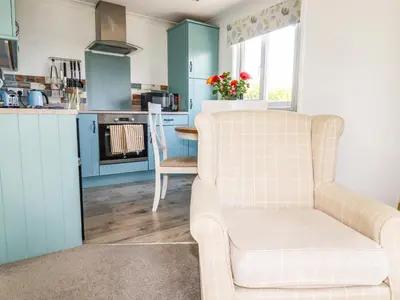 a living room with a chair and a kitchen at Hunrosa in Redruth