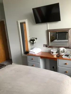 a bedroom with a bed and a desk with a mirror at Beechwood House in St Ives