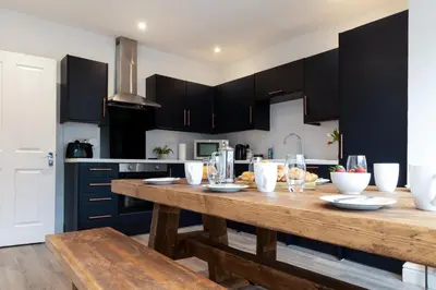 a kitchen with a wooden table and black cabinets at The Nook - Self Serviced Accommodation in St Ives