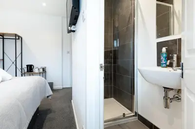 a bathroom with a shower and a sink next to a bed at The Nook - Self Serviced Accommodation in St Ives