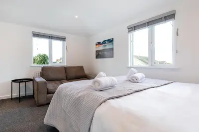 a white bedroom with a bed and a couch at The Nook - Self Serviced Accommodation in St Ives