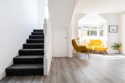 a living room with stairs and yellow chairs at The Nook - Self Serviced Accommodation in St Ives
