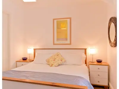 a bedroom with a bed with two night stands and two lamps at Sand Dune in Looe