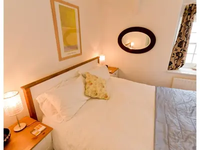 a bedroom with a white bed with a yellow pillow on it at Sand Dune in Looe