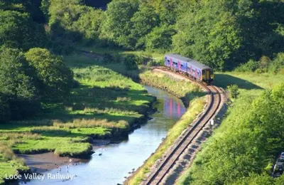 a train traveling down the tracks next to a river at Sand Dune in Looe