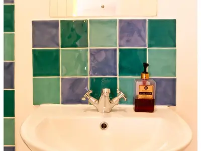 a bathroom sink with a bottle of soap on it at Sand Dune in Looe