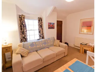 a living room with a couch and a window at Sand Dune in Looe