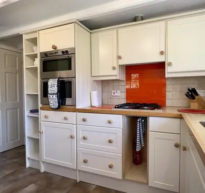a kitchen with white cabinets and a stove top oven at Tresowes Green Cottage in Helston