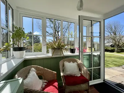 a screened in porch with two chairs and windows at Tresowes Green Cottage in Helston