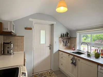 a kitchen with a white door and a window at Tresowes Green Cottage in Helston