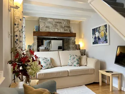 a living room with a couch and a stone fireplace at Tresowes Green Cottage in Helston