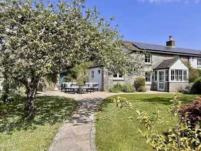 a stone house with a picnic table in the yard at Tresowes Green Cottage in Helston