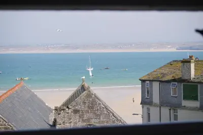 a view of a beach with a boat in the water at The Loft in St Ives