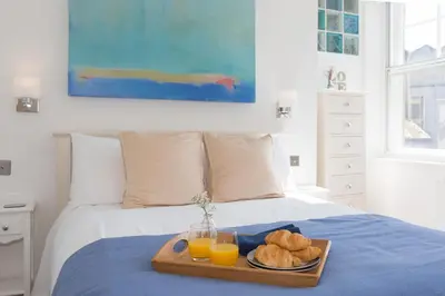 a tray of bread and orange juice on a bed at The Loft in St Ives