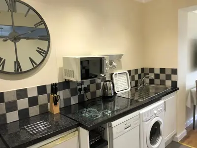 a kitchen with a sink and a clock on the wall at Seaclusion in St Austell