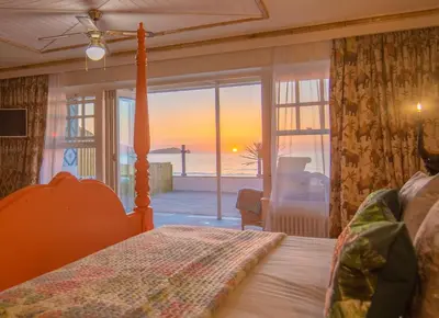 a bedroom with a bed and a view of the ocean at Tolcarne Beach Colonial Restaurant and Rooms in Newquay
