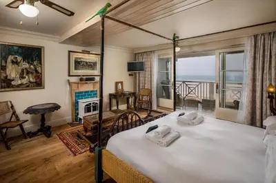 a bedroom with a bed with a view of the ocean at Tolcarne Beach Colonial Restaurant and Rooms in Newquay