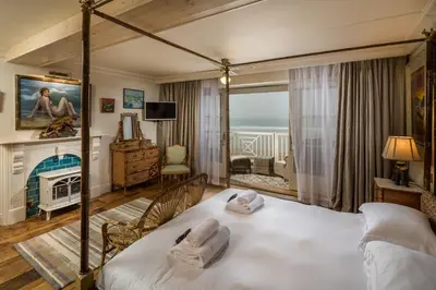 a bedroom with a large bed and a fireplace at Tolcarne Beach Colonial Restaurant and Rooms in Newquay