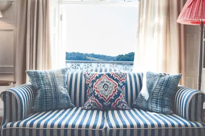 a blue and white couch with pillows in front of a window at St Mawes Hotel in Saint Mawes