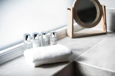 a bathroom counter with four bottles of soap and a mirror at chyreen@marazion in Marazion