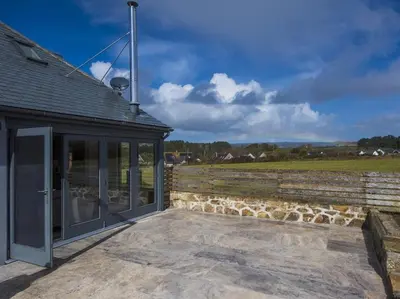 a building with glass doors and a stone wall at chyreen@marazion in Marazion