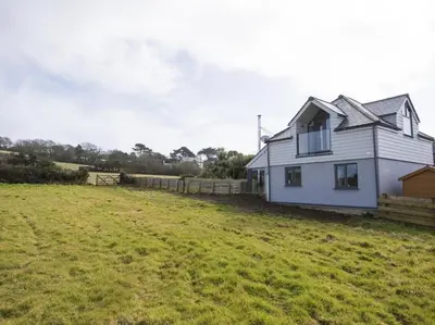 a white house in a field next to a fence at chyreen@marazion in Marazion