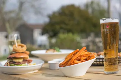 a table with a sandwich and fries and a glass of beer at Atlantic Reach Resort in Newquay