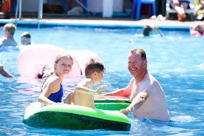 a man and two children on inflatables in a swimming pool at Atlantic Reach Resort in Newquay