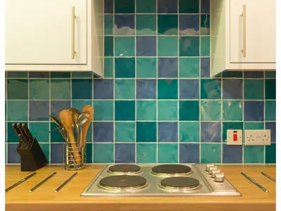 a kitchen counter with a stove top with blue tiles at Sand Martin in Looe