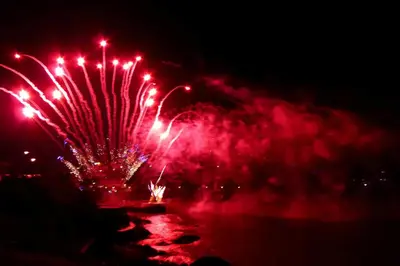 a firework display in the dark with red lights at Sand Martin in Looe