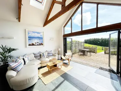 a living room with white furniture and large windows at Merlin Farm Cottages short walk to Mawgan Porth Beach and central location in Cornwall in Mawgan Porth