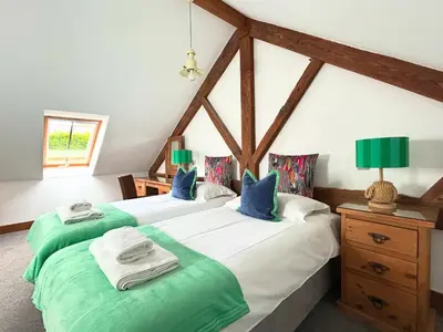 two beds with green and white sheets in a room at Merlin Farm Cottages short walk to Mawgan Porth Beach and central location in Cornwall in Mawgan Porth
