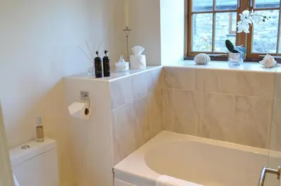 a bathroom with a tub and a toilet and a window at Tremodrett House Barn in Bodmin