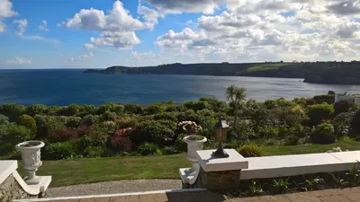 a white bench overlooking the ocean with a view at Tremodrett House Barn in Bodmin