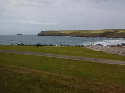 a grassy field next to the ocean with a beach at Tremodrett House Barn in Bodmin