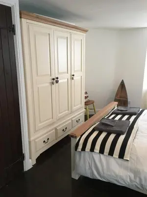 a bedroom with a white cabinet and a bed at The Old Vicarage in Looe