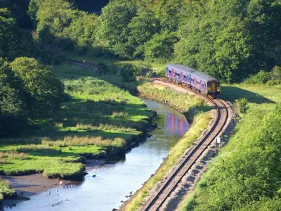 a train traveling down the tracks next to a river at The Old Vicarage in Looe