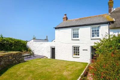 a white house with a lawn in front of it at Wrens Nook in St. Agnes
