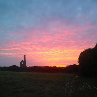 a sunset with a clock tower in a field at Wrens Nook in St. Agnes