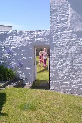 two children walking through the door of a white building at Wrens Nook in St. Agnes