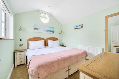 a bedroom with a large bed and a table at The Lodge, Polgooth in St Austell