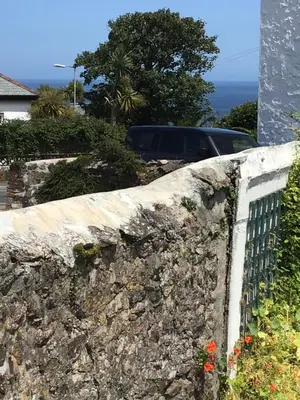 a stone retaining wall with a car in the background at Coachhouse in St Ives
