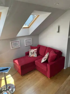 a red couch in a living room with a window at Coachhouse in St Ives