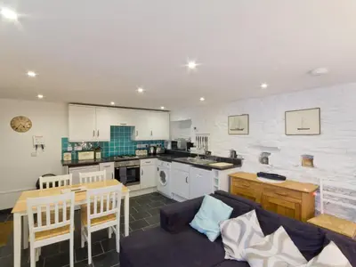 a living room with a couch and a kitchen at Museum Apartment in Looe